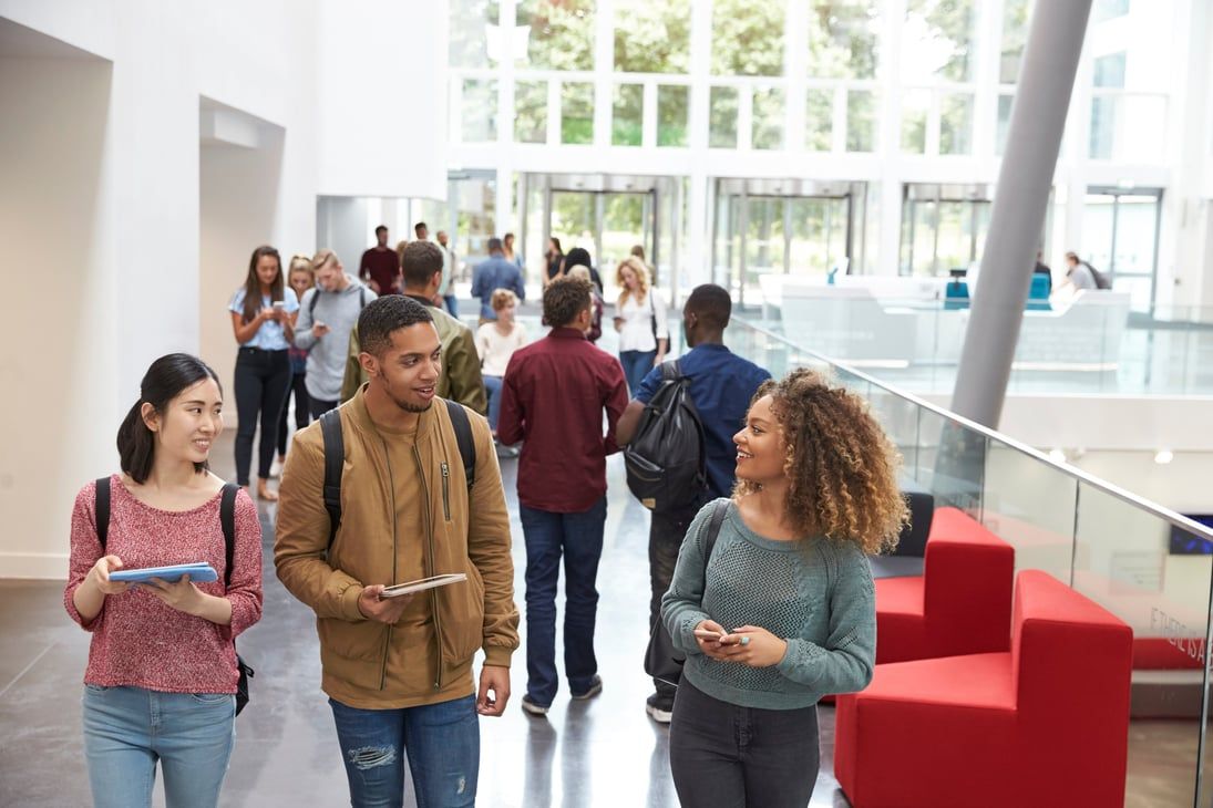 Des étudiants discutent dans le hall lumineux d'un bâtiment universitaire