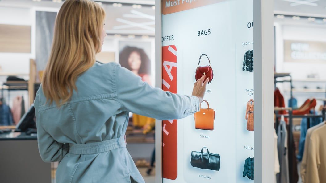 Cliente utilisant un écran tactile interactif dans une boutique