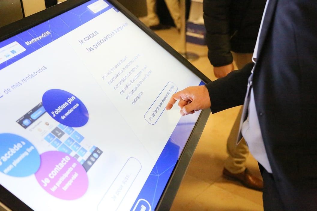 Visiteur consultant le programme du Techinnov sur une table tactile
