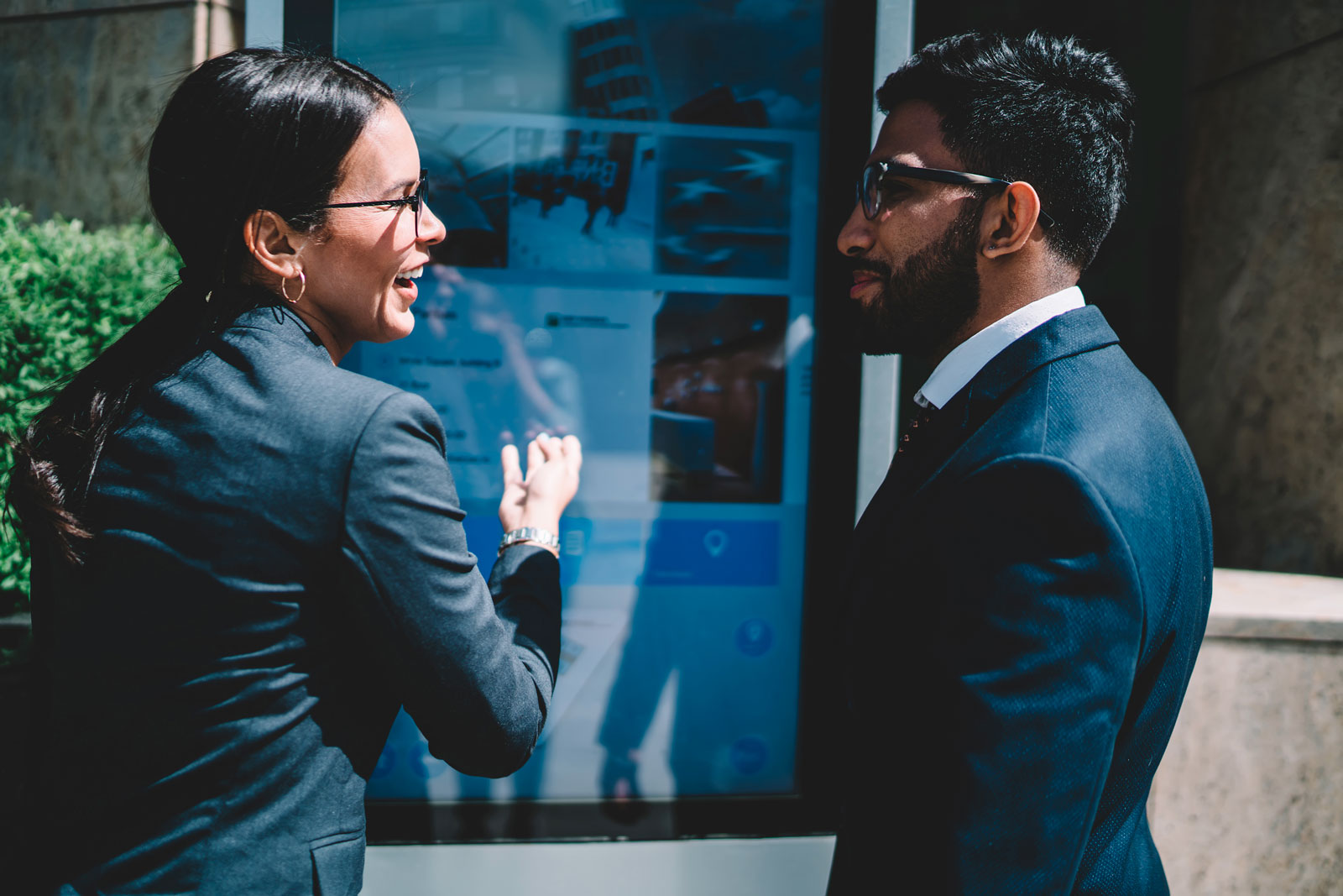 Businesswoman showing digital stand to colleague